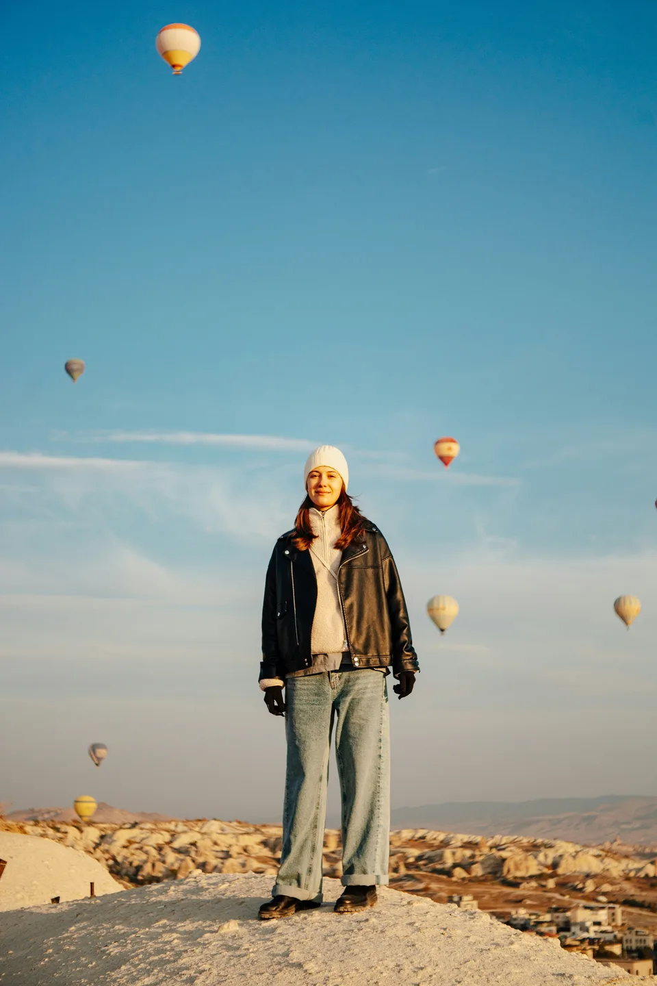 A woman posing in front of hot air balloons