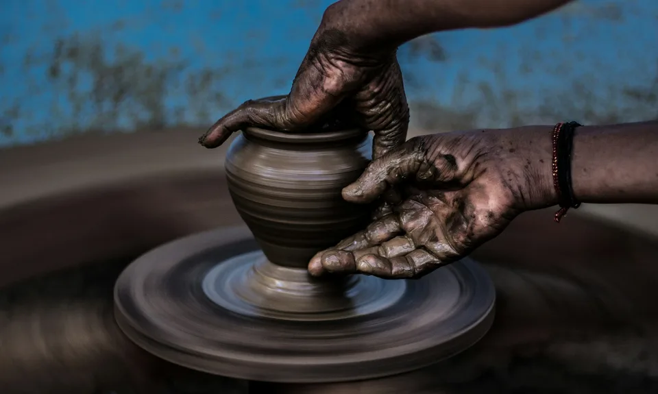 Hands shaping a clay pot on a pottery wheel